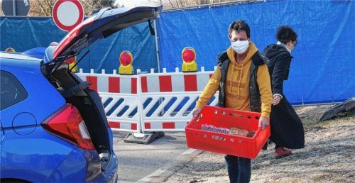 Auch bei geschlossener Grenze lief der Warenverkehr: Claudia Anker vom gleichnamigen Bergbauernhof am Niederndorferberg mit Maske beim händischen Austausch von Waren mit Mitarbeitern des Sachranger Dorfladens.Foto Kirchner