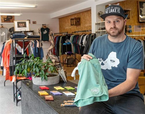 Ingemar Maier, Schöpfer der Mode seines Labels „Home is where the lake is“, im Kleidungsladen in Traunstein. Die Silhouette des Chiemsees ist das Markenzeichen. Foto Effner