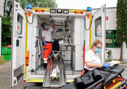 Mit dem obligatorischen Mundschutz: Die Rettungssanitäter Martin Sauro und Sophie Mayer reinigen einen BRK-Rettungswagen nach einer Einsatzfahrt. Foto Reisner