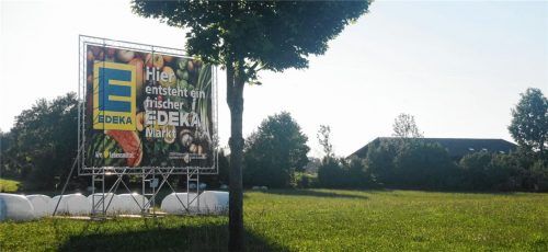 Das neueste Plakat weist auf den Markt hin. Noch allerdings liegen auf der Wiese, die überbaut werden soll, Heuballen. Foto Kirchner