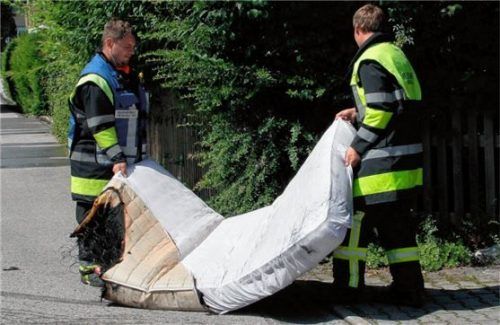 Einsatzkräfte bringen eine angebrannte Matratze aus der Wohnung. Foto Reisner