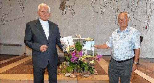Hobbyfotograf Karl Reif senior (links) überreicht Pfarrer Drago Curic den bebilderten Kirchenführer „23 Katholische Kirchen westlich des Inns“. Foto Greiner