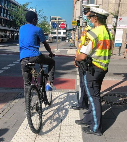 Ohne Helm und Licht: Die beiden Polizisten erklären dem jungen Mann, warum das Tragen eines Kopfschutzes sinnvoll wäre.