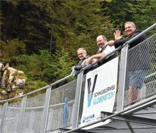 Die Bürgermeister von Kössen und Schleching, Reinhold Flörl und Josef Loferer, grüßen mit Obmann Gerd Erharter vom Tourismusverband Kaiserwinkel (von links) von der neuen Hängebrücke.