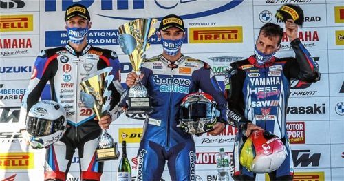 Die Freude ist unter der Maske zu erahnen: Siegerehrung in der IDM mit Motorradpilot Jonas Folger (Mitte).