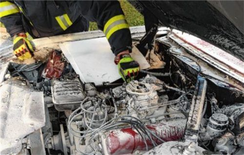 Ein Mitglied der Feuerwehr begutachtet den Schaden im Motorraum..