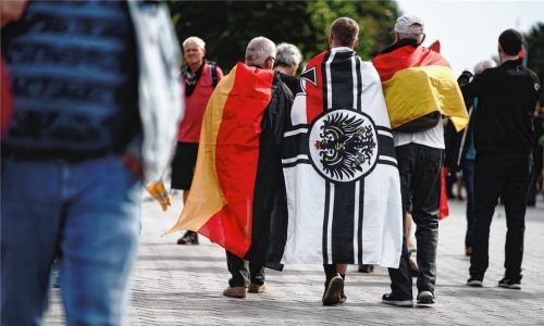 Ein Teilnehmer einer Demonstration gegen die Corona-Maßnahmen hat sich eine Reichskriegsflagge über die Schultern gelegt. Eine derartige Flagge soll der angeklagte Kripobeamte auch in seinem Büro gehabt haben. Foto dpa