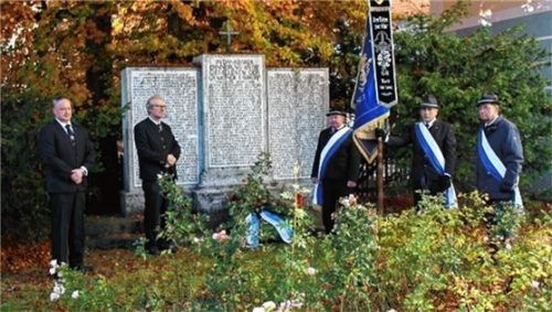 Vorsitzender Konrad Schauer (Zweiter von links) und Stellvertreter Martin Mühlnickel (links) legen mit der Fahnenabordnung einen Kranz am Kriegerdenkmal nieder. Foto RE