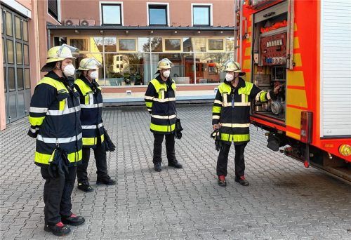 Zur Schutzkleidung kommt die Mund-Nasen-Bedeckung hinzu: Johann Zehentner (von links), Peter Perl, Alexander Moneti und Sebastian Hauenstein stehen einsatzbereit am Löschfahrzeug. Foto Freiwillige Feuerwehr Rosenheim