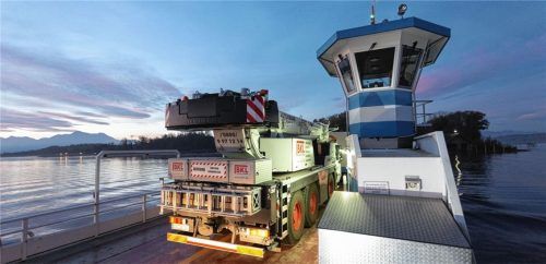 Noch vor Sonnenaufgang schippert die Lastfähre mit dem Mobilkran an Bord über den Chiemsee zur Herreninsel. Dort werden die großen Felsenbrunnen am neuen Schloss für den Winter abgedeckt.Foto Liebherr