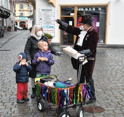Helmut Müller bietet Lydia Hirsch und ihren Enkelkindern Mavi und Benni auf dem Max-Josefs-Platz Krapfen an. Foto Schlecker