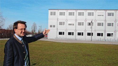 Hier soll der Neubau entstehen. Bürgermeister Stephan Schlier zeigt auf das Areal, auf dem das Staatsinstitut errichtet werden soll. Im Hintergrund sind die Schulcontainer zu sehen, in denen derzeit der Unterricht für die Schüler der St.-Georg-Schule stattfindet.Foto Hadersbeck