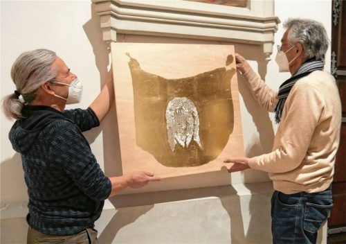 Jörg Länger zeigt heuer in der Fastenzeit in St. Nikolaus seinen eigens für die Rosenheimer Pfarrkirche konzipierten Kreuzweg „Das Vera Icon in 14 Stationen seiner Passion“. Hausherr Pfarrer Andreas Maria Zach (rechts) hilft dem in Rohrdorf lebenden Künstler hier beim Aufhängen des Vera Icon, des wahren Antlitzes Christi, das im „Schweißtuch der Veronika“ namensgebend wirkt. Foto Frick