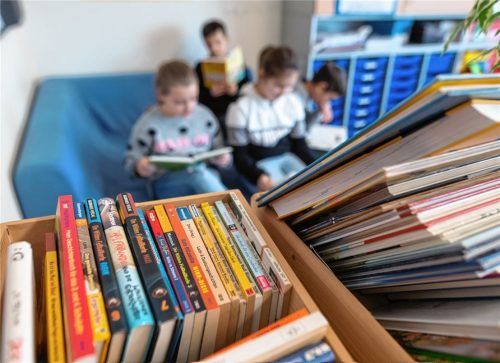 Kinder sitzen vor einer Kiste Bücher und lesen einander vor. Der Rosenheimer Stadtentscheid des bundesweiten Vorlesewettbewerbs findet heuer aufgrund der Corona-Pandemie nur online statt. Fotos dpa/Schlecker
