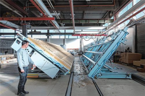 Blick in die Montagehalle: Ein Mitarbeiter von Regnauer Fertigbau steht an einer Wendevorrichtung. Durch die wetterunabhängige industrielle Vorfertigung von Holzbauteilen am Firmenstandort in Seebruck lässt sich die Montagezeit auf der Baustelle deutlich verkürzen.Fotos  re