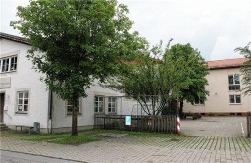Nach den Vorstellungen des Plenums soll der Zaun bis zur Grundstücksgrenze nach Norden (Vordergrund) gezogen werden. Nach dem Abbruch der alten Gemeindeverwaltung und der bisherigen Turnhalle (links) ist der entstehende Raum für Spielgeräte und einen Fahrradunterstand vorgesehen. Das Fußballtor bleibt den Kindern im Pausenhof erhalten. Der Zugang zur neuen Schule (hinten, Mitte) bleibt bestehen.Foto Rehberg