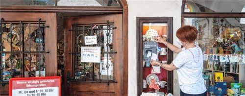 Nur noch mit Test: Anne Donath bringt an ihrem Geschäft gegenüber vom Wasserburger Rathaus das entsprechende Hinweisschild an. Foto John Cater