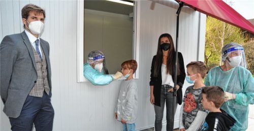 Rohrdorfer Grundschüler können seit dieser Woche Schnelltests in der Apotheke in Thansau machen. Möglich gemacht haben das Bürgermeister Simon Hausstetter (Bürgerblock Rohrdorf, links), Elternbeiratsvorsitzende Bernadette Hollinger (Vierte von links) und Gabriele Prankl, Leiterin des Sozialwerks (rechts). Hier testet ein Mitarbeiter der Apotheke Hollingers Sohn Louis.Foto Schlecker