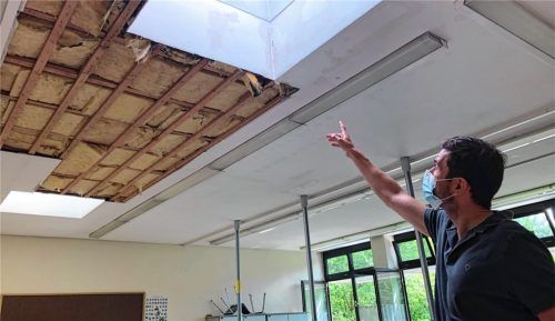 Nach dem Hagelsturm  war Wasser durch die Decke gedrungen. Schulleiter Alexander Ruß deutet auf die Dämmung, die sich mit Wasser voll gesaugt hat. Foto  Grundner
