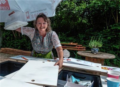 Brigitte Plank zeigt, dass die rollende „Plauder-Bar“ bestens ausgerüstet ist: Neben Stühlen finden im Anhänger auch Kaffee und Kuchen Platz.