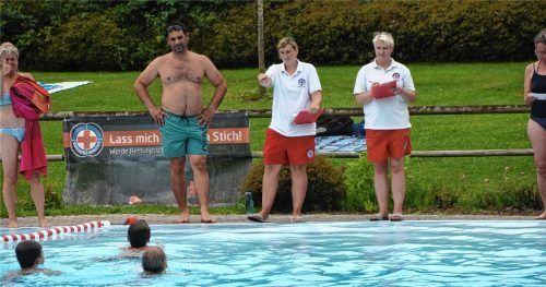 Drei Kinder sind auf der Schwimmstrecke, beobachtet von den Mitgliedern der BRK Wasserwacht Ortsgruppe Flintsbach Tamara Streifeneder (links) und Marion Bornemann im rot-weißen Wasserwacht-Dress.Foto Ruprecht