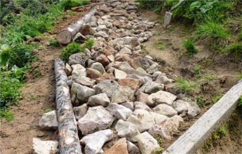 Mit Steinen und Hölzern werden die Wanderwege am Geigelstein stabilisiert.