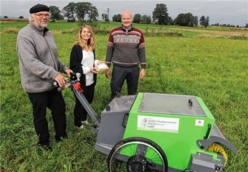 Alexa Hubert, von der Sparkassenstiftung Zukunft ließ sich die Maschine zur Ernte der Blumensamen von Landwirt Konrad Schinkinger (links), Eigentümer der Versuchsfläche auf den Panger Feldern, sowie Markus Höper vom Landschaftspflegeverband zeigen. Foto Sparkassenstiftungen Zukunft