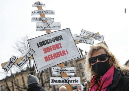 Eine Teilnehmerin der Demonstration gegen Maßnahmen der Bundesregierung zur Eindämmung der Corona-Ausbreitung hält ein Holzkreuz mit Zetteln hoch. Foto dpa