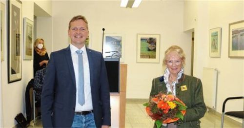Ihre Werke stellt Gudrun Glück bis Ende April 2022 im Aschauer Rathaus aus. Bürgermeister Simon Frank bedankt sich mit einem Blumenstrauß für ihr Engagement.Foto Rehberg