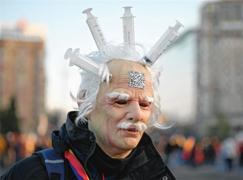 Ein Demonstrant, der gegen den „Grünen Pass“ protestiert, trägt eine Latexmaske mit daran befestigten Spritzen während einer Kundgebung. Foto dpa