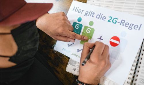 Ein Friseur zeichnet ein „Plus“ auf ein Schild, das auf die 2G-plus-Regel hinweisen soll. Foto dpa