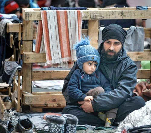Ein Mann mit seinem Kind, die sich in einem Logistikzentrum am Kontrollpunkt „Kuznitsa“ ausruhen. Der belarussische Präsident Lukaschenko steht in der Kritik, tausende Menschen, die bei eisigen Temperaturen im Grenzgebiet ausharren, in diese schwierige Lage gebracht zu haben. Foto dpa