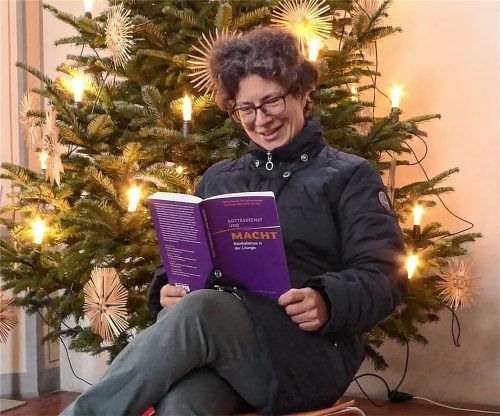 Vor dem hell erleuchteten Weihnachtsbaum in der Stadtkirche Kolbermoor liest Pastoralreferentin Martina Mauder (48) das Buch „Gottesdienst und Macht: Klerikalismus in der Liturgie“. Fotos Riediger (1)/RE (8)