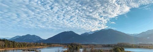 Am Himmel über der Moorlandschaft der „Nicklheimer Fuizn“, am Fuß von Sulzberg und Farrenpoint, sind kleine Schäfchenwolken zu sehen. Man könnte meinen, ein entfernter Vulkan in den Bergen würde weiße Rauchwolken über die Landschaft blasen. Foto Binder