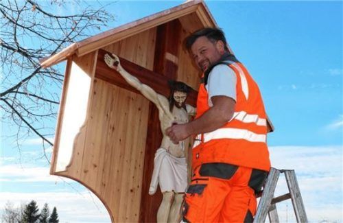 Guter Halt: Peter Bauer befestigt das restaurierte Kruzifix unter seinem Schutzdach.
