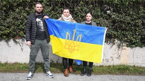 Oleksii Sysoier, seine Frau Julia Betsova und Iryna Inninger (von links) aus Prien halten die Fahne ihres Heimatlandes Ukraine hoch. Sie sind bestürzt über den Krieg und machen sich große Sorgen. Foto Weichold