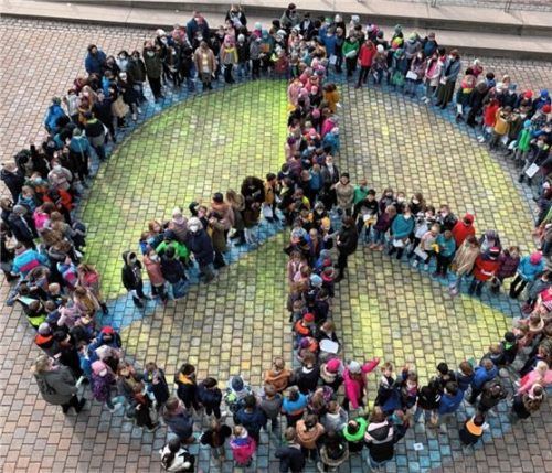 Rund 300 Schüler bildeten das riesengroße aufgemalte Friedenszeichen vor der Mangfallschule nach. Foto re