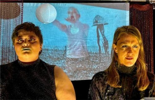 Annika Roth und Jennifer Seeger spielen vor einem an die Wand projizierten Postkartenidyll. Foto re