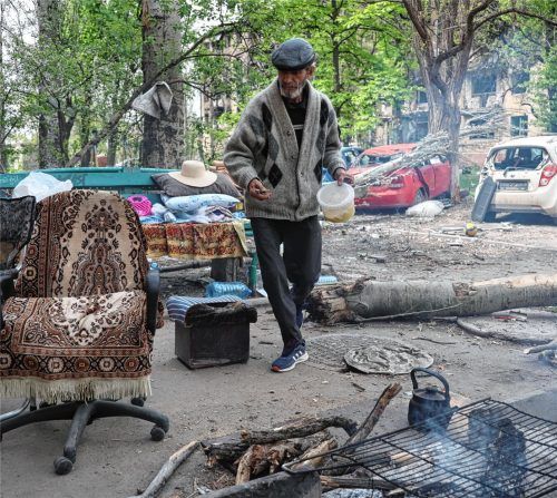 Ein Mann kocht neben seinem Haus in Mariupol, der weitgehend zerstörten Stadt im Osten der Ukraine. Foto dpa