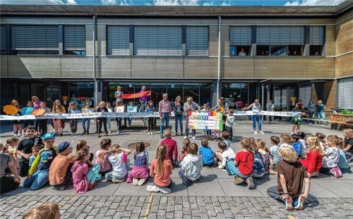 Übergabe des Geldes: Bei einem kleinen Schulfest der Grund- und Hauptschule Brannenburg erhielt Pfarrer Thomas Löffler (rotes Hemd, stehend) 4000 Euro für den Helferkreis. Stolz auf die Kinder waren Schulleiterin Alexandra Mayr (stehend, Zweite von links) und Bürgermeister Matthias Jokisch (stehend, Dritter von links). Foto Thomae