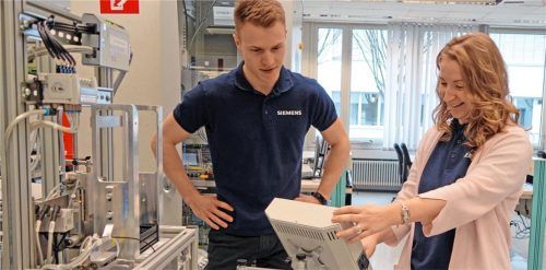 An der Automatisierungstechnikanlage lernen die Studierenden viel für ihren späteren Beruf. Mentorin Susan Michelchen unterstützt sie dabei. Foto djd/Siemens Professional Education