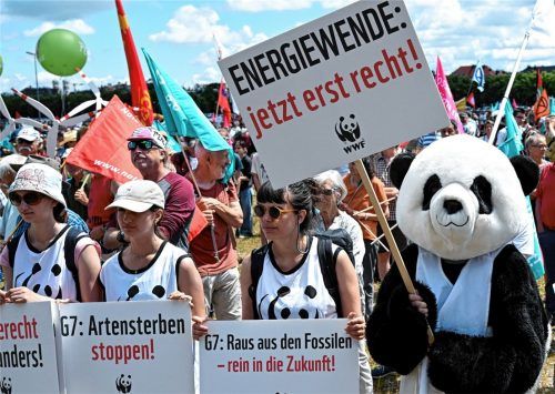 Ein als Panda kostümierter Teilnehmer hält ein Schild mit der Aufschrift „Energiewende: jetzt erst recht!“ bei einer Demonstration gegen den G7-Gipfel. Foto dpa
