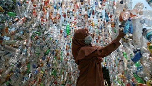 Eine Frau steht während einer Umweltkampagne in einer Installation aus Plastikflaschen. Foto dpa