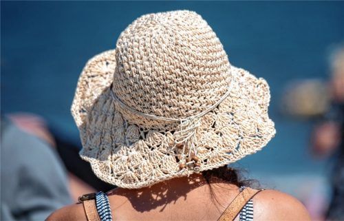 Eine Strandbesucherin hat sich bei Temperaturen von knapp 30 Grad einen Strandhut aufgesetzt. Foto dpa