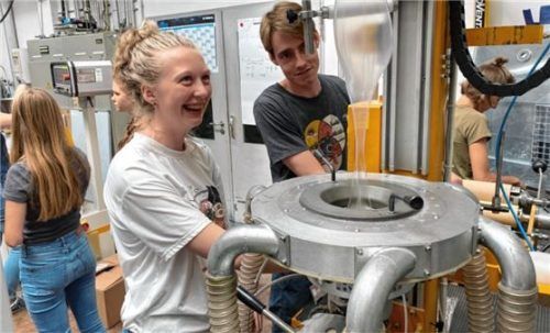 Jonas Herz, Mitarbeiter im Technikum Kunststoffverarbeitung, demonstriert einer Teilnehmerin des Feriencamps die Blasfolienherstellung.Foto re