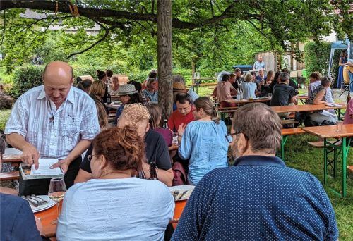 Pfarrer Günter Nun (links) verteilt im idyllischen Kirchhof den Fragebogen für das Umweltquiz. Foto hoffmann