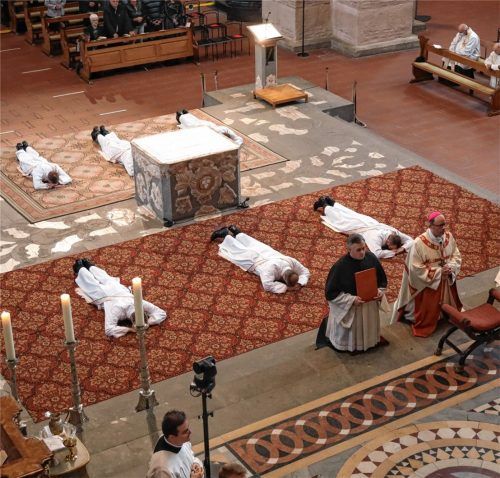 Sechs Männer liegen beim Gottesdienst zu ihrer Priesterweihe auf dem Boden im Trierer Dom, während Bischof Stephan Ackermann (rechts) vor ihnen kniet. Foto dpa
