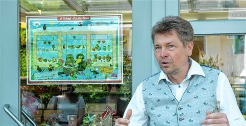 Von der Aktion ist der Vorsitzende des Gewerbevereins Aschau, Rainer Küblbeck, begeistert. Im Hintergrund ist ein Wimmelbild zu sehen. In ihm versteckt sich ein Buchstabe.Foto  Berger