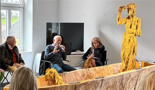 Andreas Kuhnlein (Mitte)  teilt in der Galerie im Alten Rathaus mit den Gästen Gedanken zu seiner künstlerischen Arbeit, die den Menschen in den Mittelpunkt stellt. Ein Baum mit seinen Jahresringen, so Kuhnlein, „trägt die verflossene Zeit ebenso in sich wie ein menschliches Antlitz“. Foto  Prien Marketing GmbH