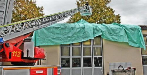 Mithilfe einer Drehleiter kann eine spezielle Plane über ein beschädigtes Dach gezogen werden. Foto Binder